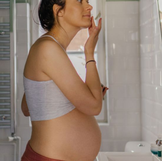 Pregnant woman applying treatment to face